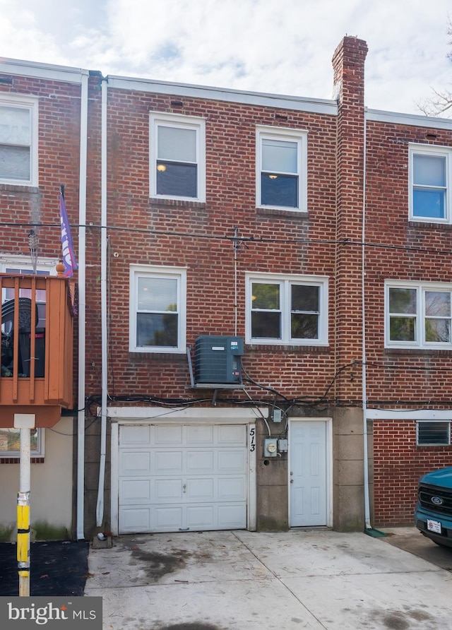 view of front of home with a garage, brick siding, central AC unit, and driveway