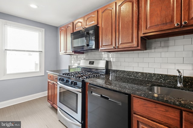 kitchen with dark stone counters, a sink, black microwave, dishwasher, and stainless steel gas stove