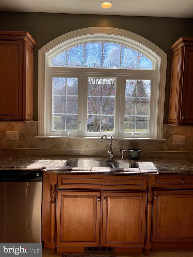 interior space featuring brown cabinetry, a sink, decorative backsplash, and stainless steel dishwasher