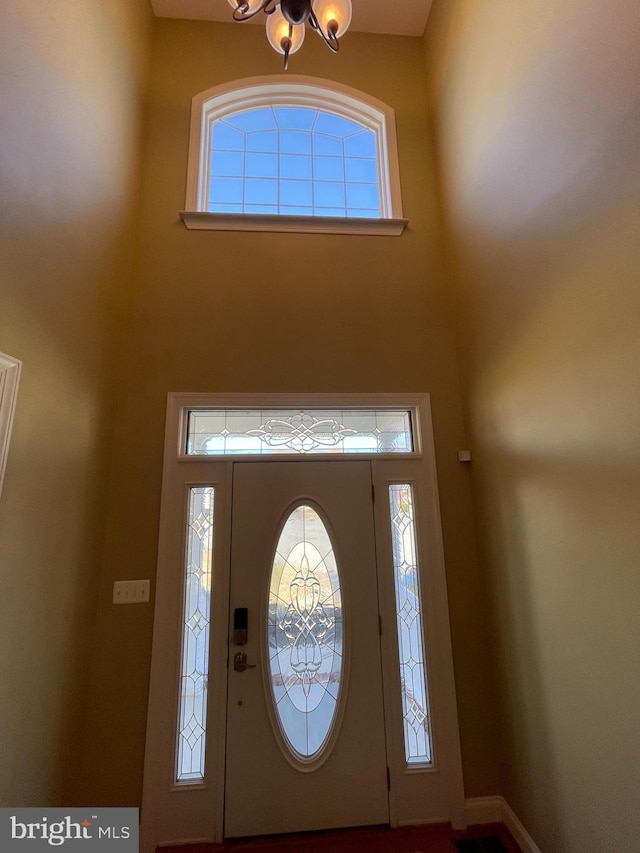 entrance foyer with a towering ceiling, plenty of natural light, and a chandelier