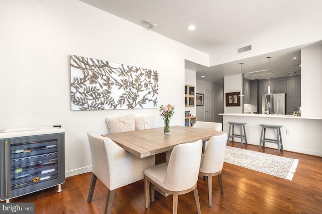 dining room with heating unit, baseboards, visible vents, and dark wood-style flooring