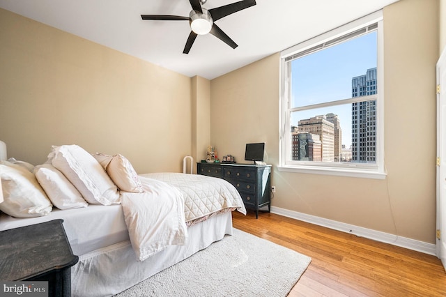 bedroom featuring ceiling fan, baseboards, and wood finished floors