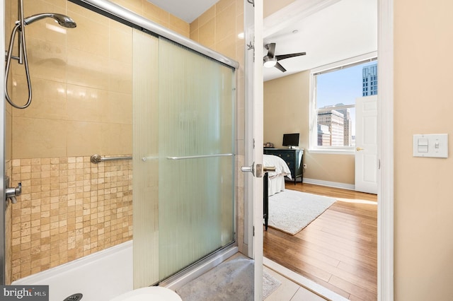 ensuite bathroom featuring wood finished floors, a ceiling fan, a stall shower, and ensuite bathroom