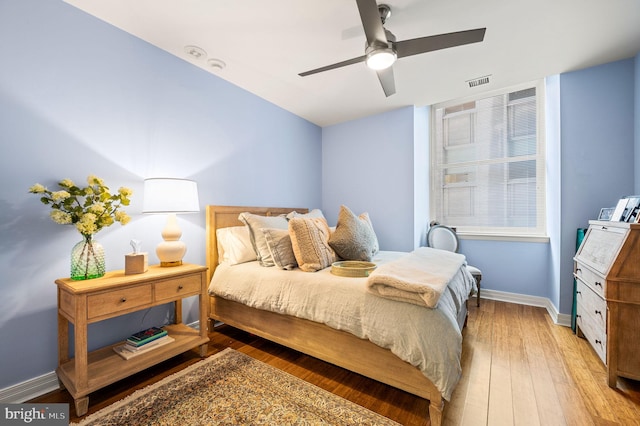 bedroom featuring hardwood / wood-style floors, baseboards, visible vents, and ceiling fan