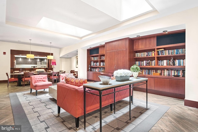 interior space with built in features, a skylight, a tray ceiling, and baseboards