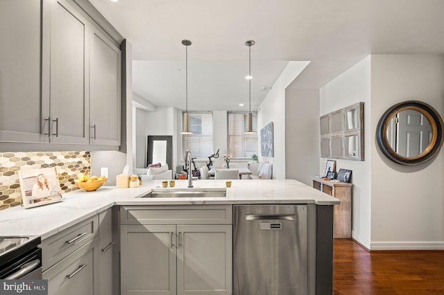 kitchen with a peninsula, a sink, gray cabinetry, stainless steel dishwasher, and tasteful backsplash