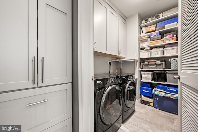 clothes washing area featuring wood finished floors, cabinet space, and washing machine and dryer