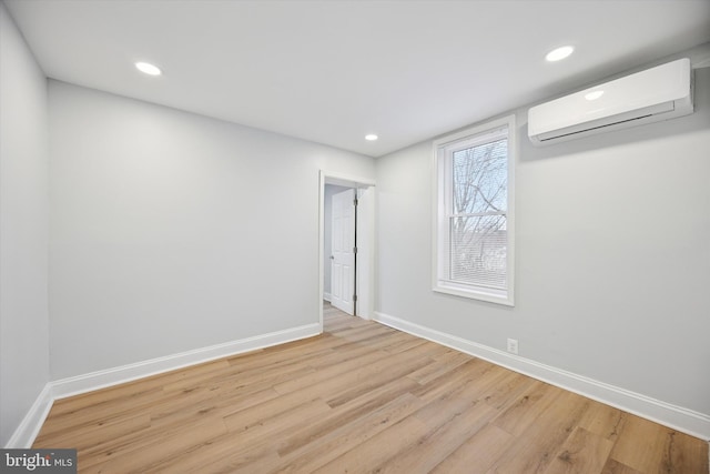 unfurnished room featuring baseboards, wood finished floors, and a wall mounted AC