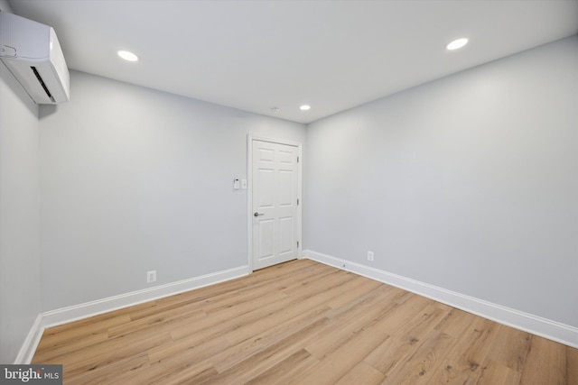 empty room featuring recessed lighting, baseboards, light wood-type flooring, and a wall mounted AC