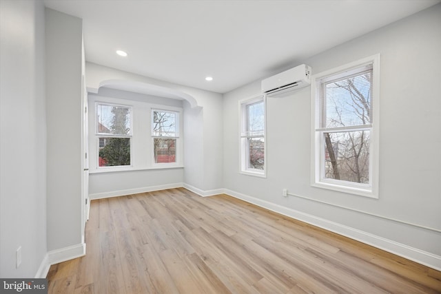 unfurnished room featuring light wood finished floors, recessed lighting, a wall mounted AC, and baseboards