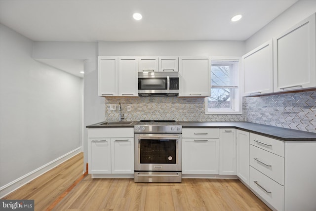 kitchen featuring dark countertops, light wood-style flooring, white cabinetry, and stainless steel appliances