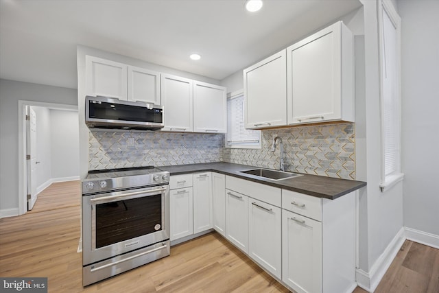 kitchen featuring dark countertops, decorative backsplash, appliances with stainless steel finishes, and a sink