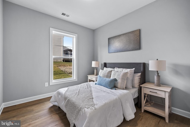 bedroom featuring baseboards, visible vents, and wood finished floors