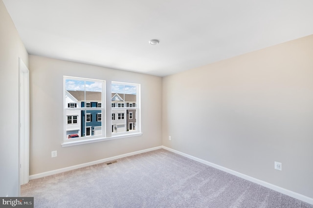 carpeted empty room featuring visible vents and baseboards