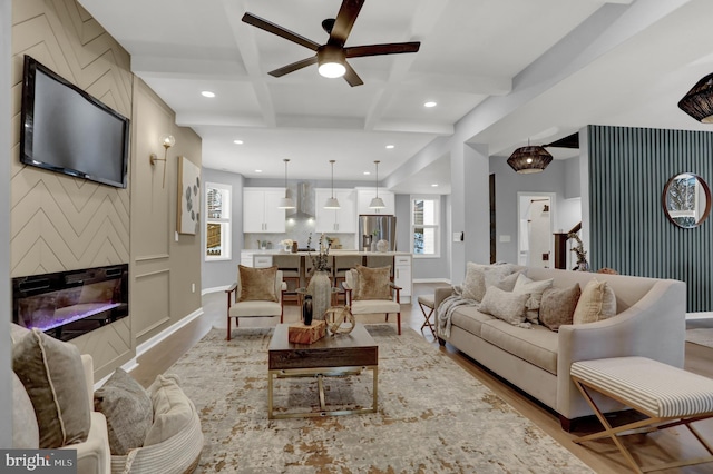 living area with coffered ceiling, plenty of natural light, light wood finished floors, and beamed ceiling