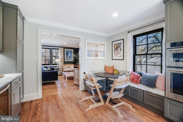 dining space with breakfast area, baseboards, crown molding, and light wood finished floors