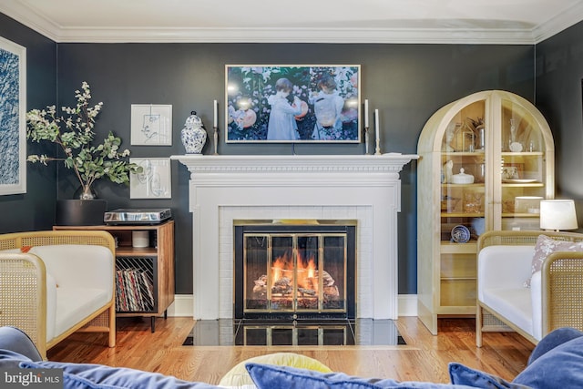 living room featuring a fireplace with flush hearth, crown molding, and wood finished floors