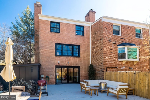 rear view of house with brick siding, a patio, and a chimney