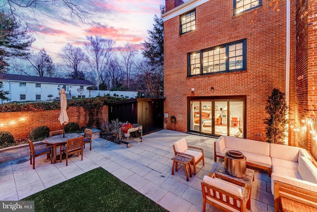 patio terrace at dusk with an outdoor living space with a fire pit