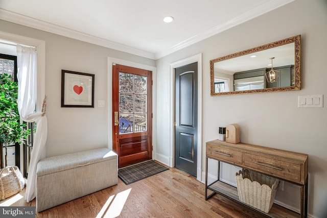 foyer with a healthy amount of sunlight, baseboards, crown molding, and wood finished floors