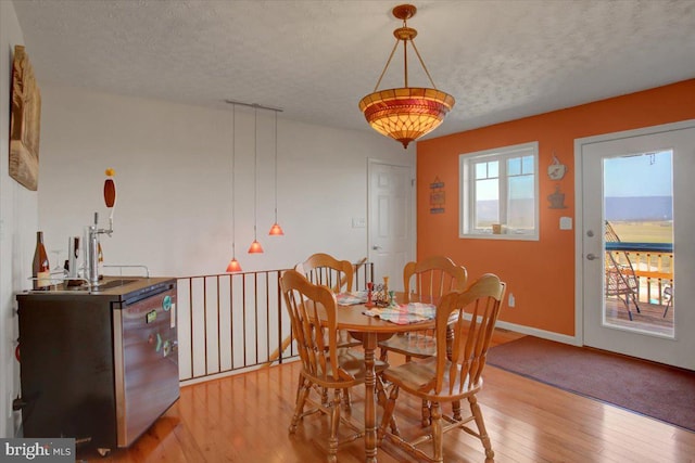 dining room with light wood-type flooring, baseboards, and a textured ceiling