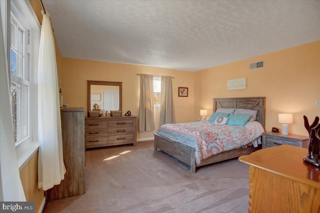 carpeted bedroom with a textured ceiling and visible vents