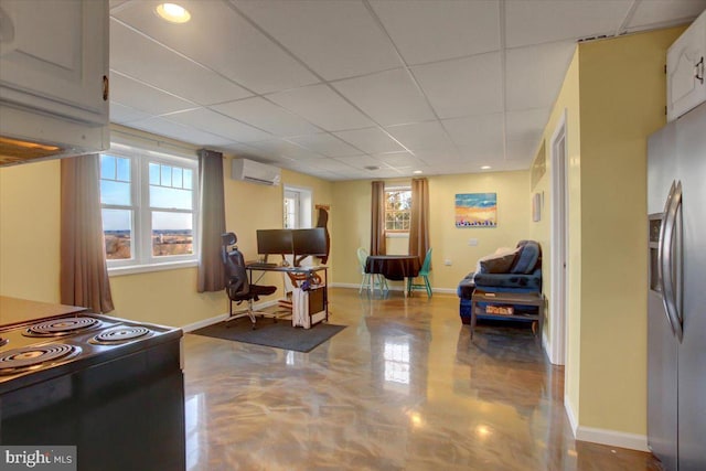 interior space with a wall mounted AC, stainless steel fridge, a wealth of natural light, and baseboards