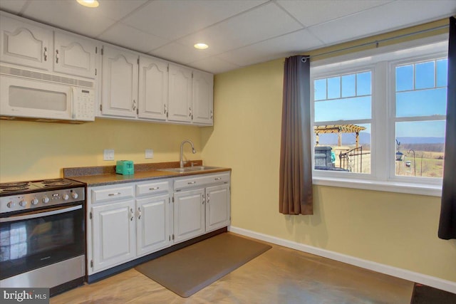 kitchen featuring white microwave, stainless steel electric range oven, white cabinetry, and a sink