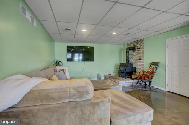 living area with a wood stove, baseboards, visible vents, and a paneled ceiling