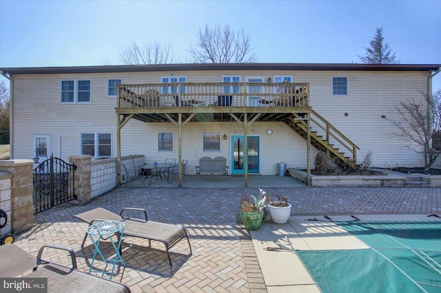 rear view of property with a deck, a patio, stairs, and fence