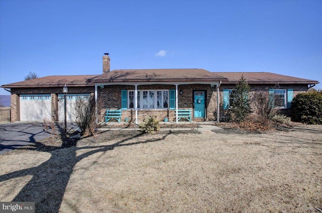 ranch-style home with driveway, a chimney, an attached garage, covered porch, and brick siding