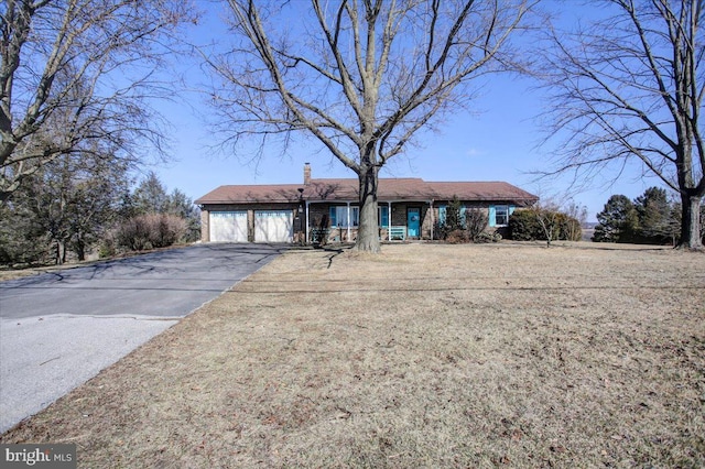 single story home featuring a garage, a chimney, and aphalt driveway