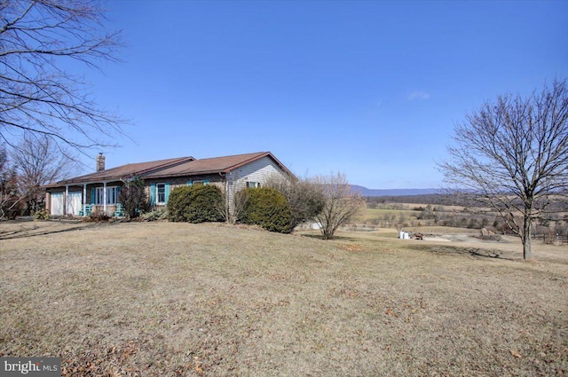 exterior space featuring an attached garage, a chimney, and a front yard