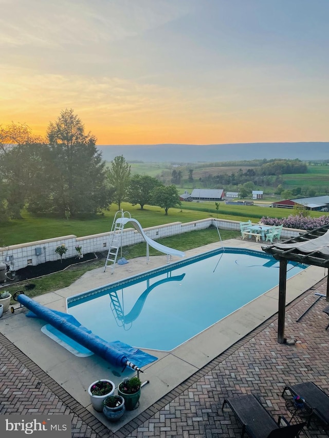 view of pool featuring a fenced backyard, a fenced in pool, a water slide, and a patio