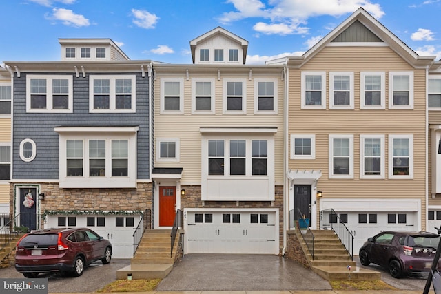 view of property with aphalt driveway, stone siding, and an attached garage