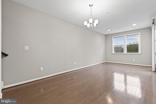 unfurnished room featuring dark wood-style floors, a notable chandelier, recessed lighting, and baseboards