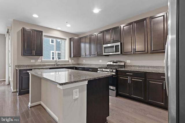 kitchen featuring a center island, stainless steel appliances, light wood-style floors, and a sink