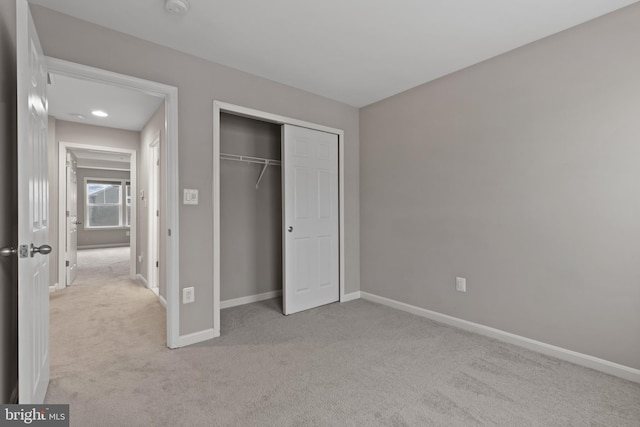 unfurnished bedroom featuring light colored carpet, baseboards, and a closet