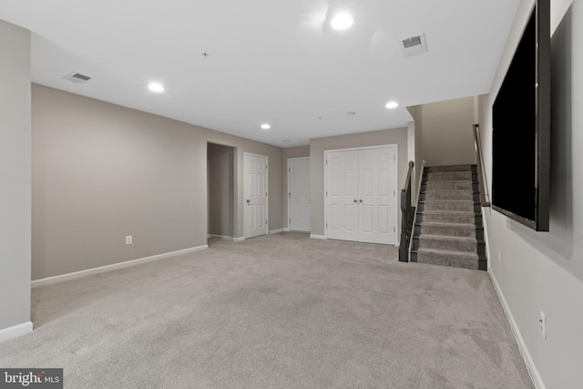 unfurnished living room with light carpet, stairway, baseboards, and visible vents