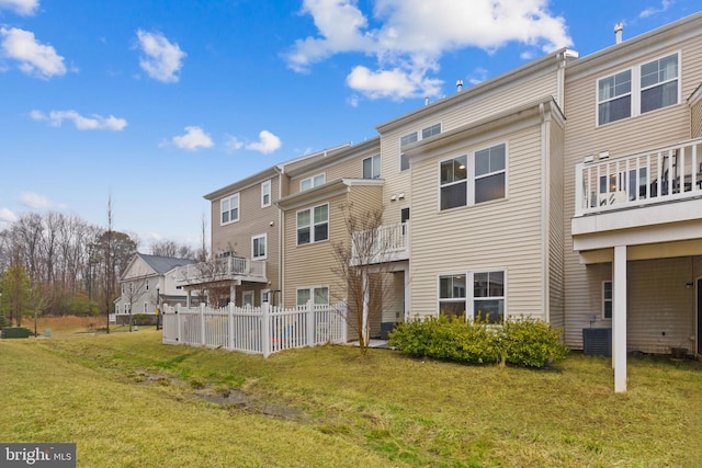 back of property featuring fence, cooling unit, a lawn, and a residential view