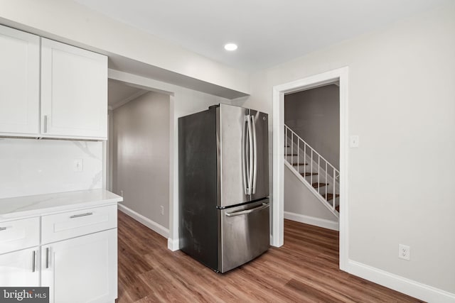 kitchen featuring baseboards, light wood-style flooring, freestanding refrigerator, and white cabinetry