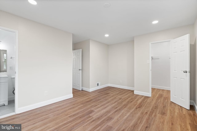 interior space featuring light wood finished floors, a spacious closet, baseboards, and recessed lighting