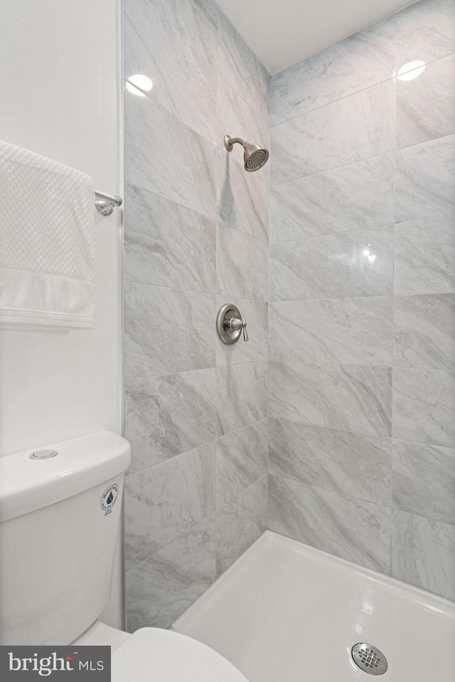 full bath featuring a tile shower and toilet