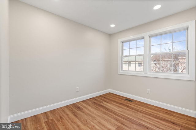 unfurnished room with light wood-type flooring, visible vents, baseboards, and recessed lighting