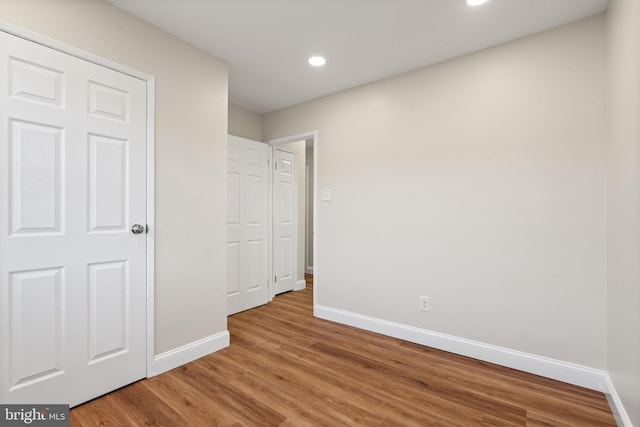 unfurnished bedroom with recessed lighting, light wood-type flooring, and baseboards