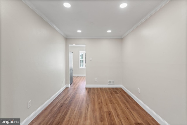 empty room featuring baseboards, visible vents, wood finished floors, crown molding, and recessed lighting