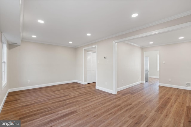 spare room featuring light wood-style floors, baseboards, and crown molding