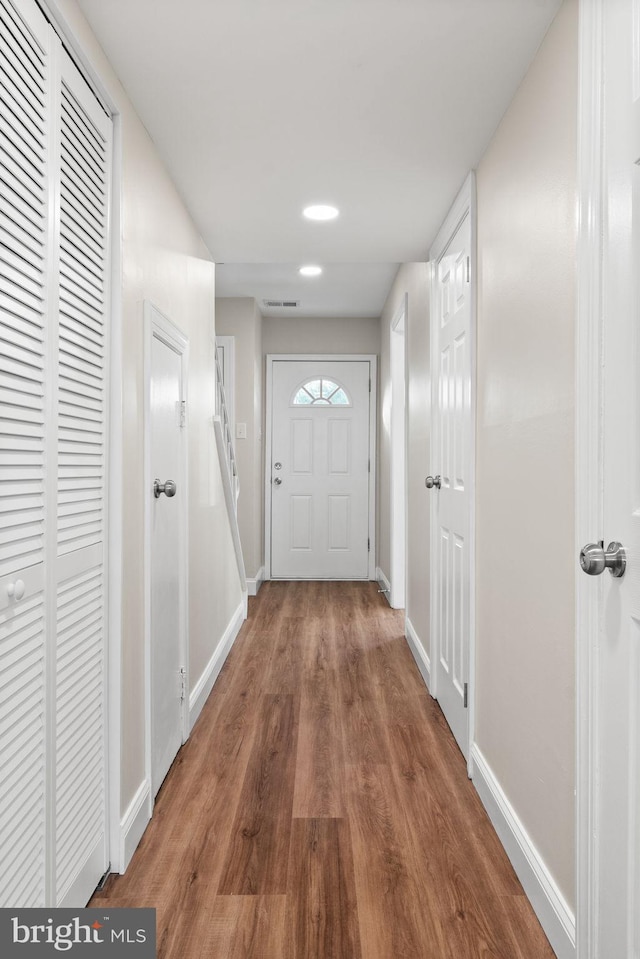 doorway with visible vents, baseboards, and wood finished floors