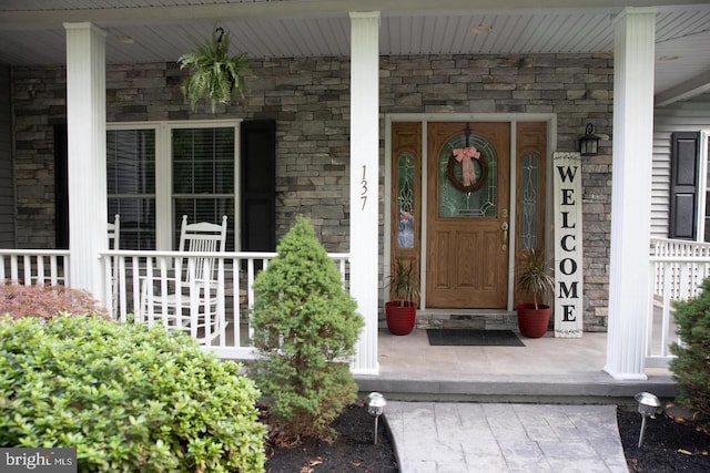 view of exterior entry featuring a porch and stone siding