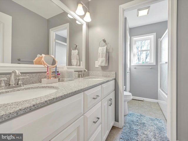 bathroom with double vanity, tile patterned flooring, a sink, and toilet